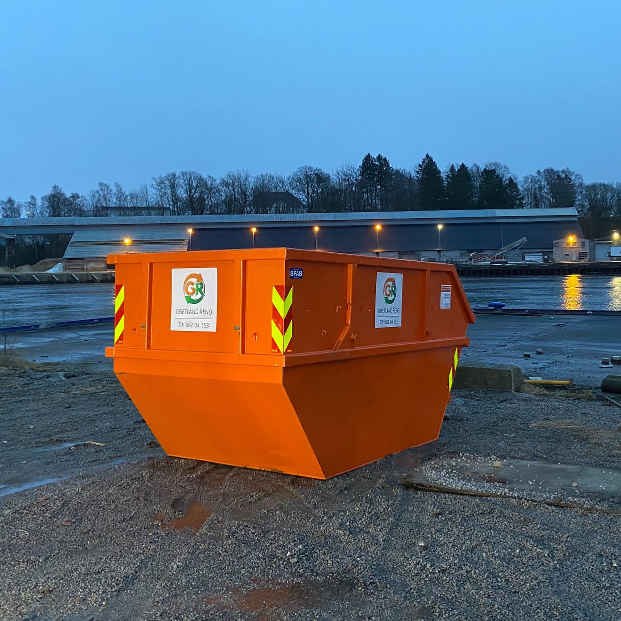 Avfallscontainer på byggeområde på kveldstid